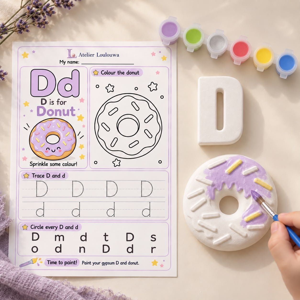 A child painting a gypsum donut beside the gypsum letter D and the D is for Donut activity card