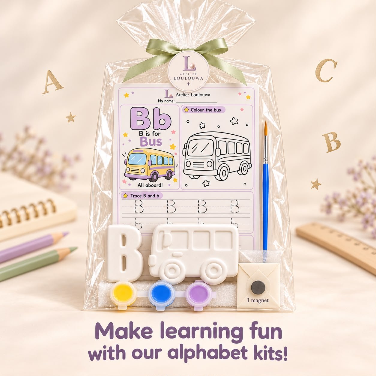The B kit as an example: a gypsum letter B and a gypsum bus, the B is for Bus activity card, three paint pots, a paintbrush and a magnet, in a transparent gift bag tied with a ribbon
